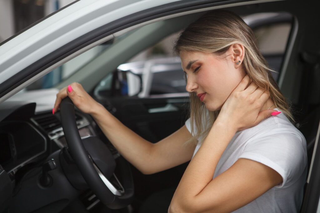 A woman holds her neck and shows signs of discomfort after a car accident.