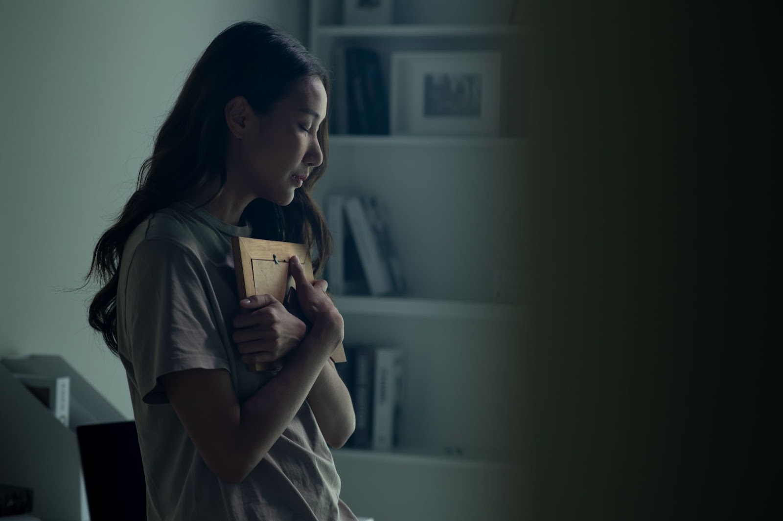 A woman holds a photograph of a loved one close to her chest.