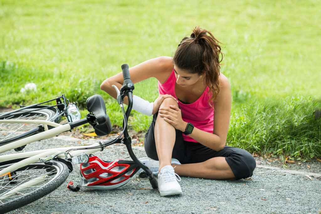 A woman holds her knee after a bicycle accident.