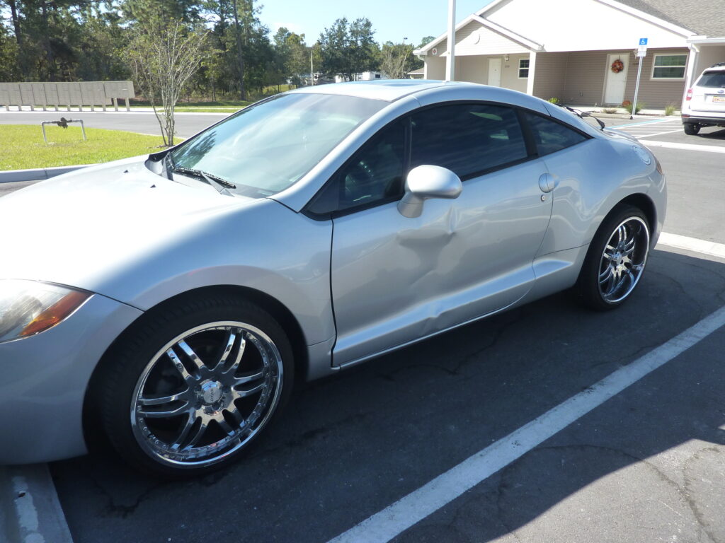 a silver car with side panel damage after a car accident.