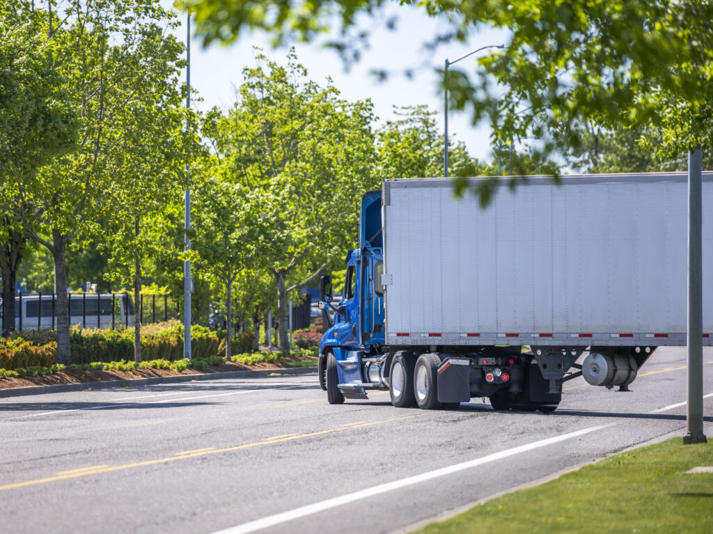 A semi-truck taking a wide right turn onto a city street.