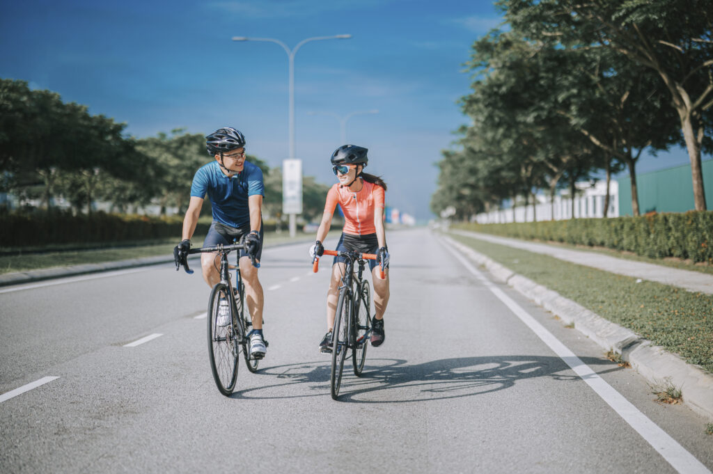 A man and a woman ride their bicycles in the street.