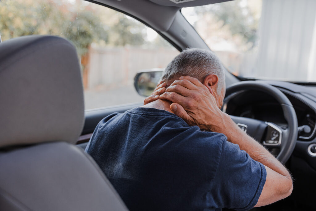 A man grabs the back of his neck in pain after a car accident.