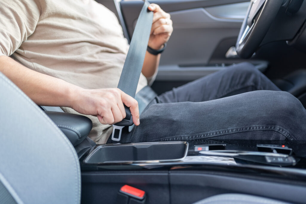 A man fastens his seat belt before starting a trip.