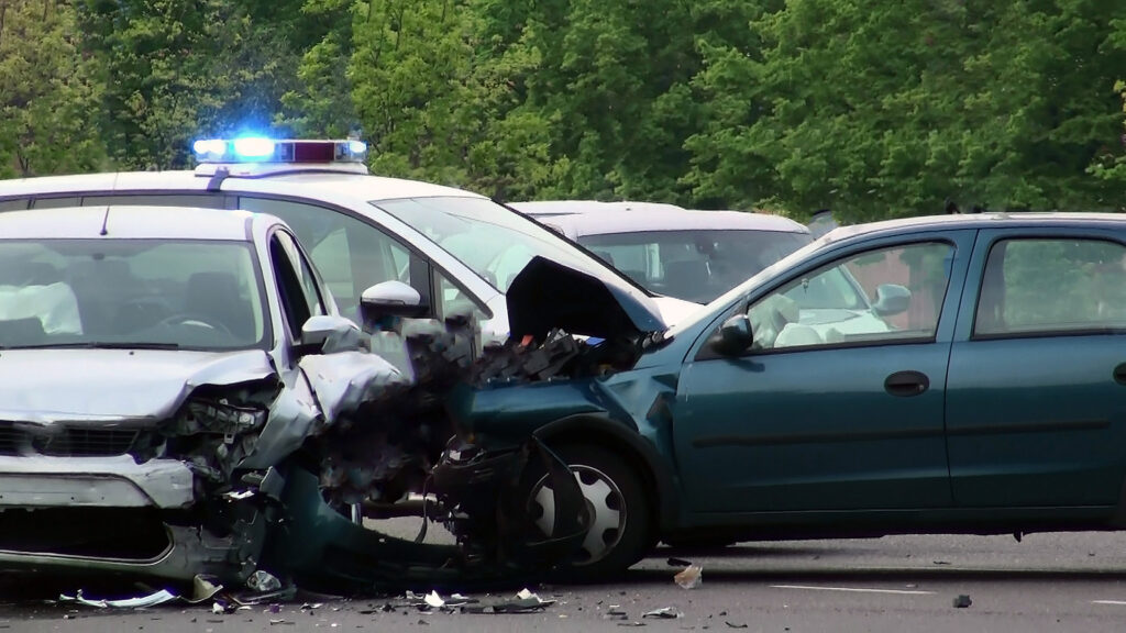 A car accident scene with a blue sedan that t-boned a grey sedan at an intersection. 